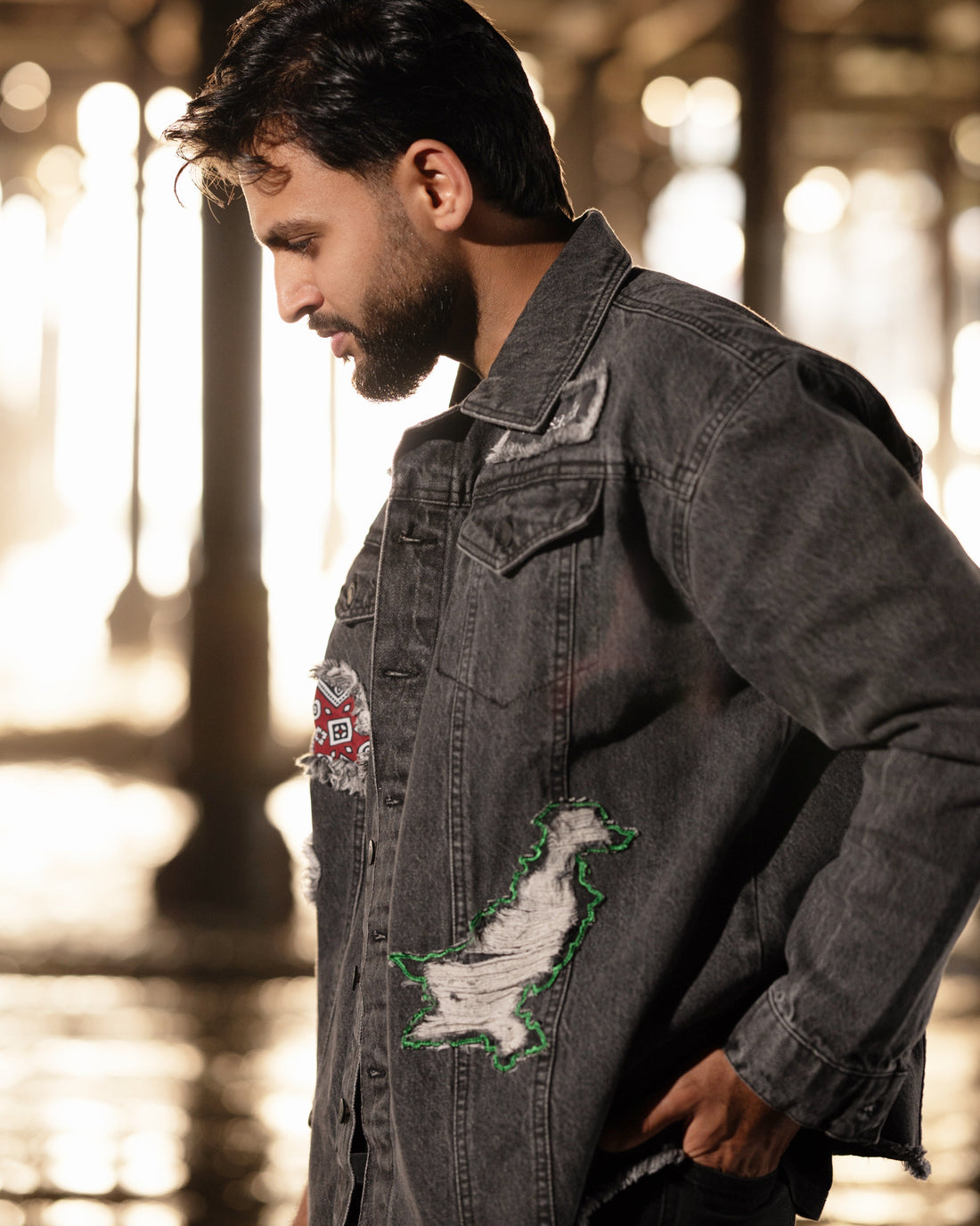 Man wearing a dark denim jacket with patches in an urban setting