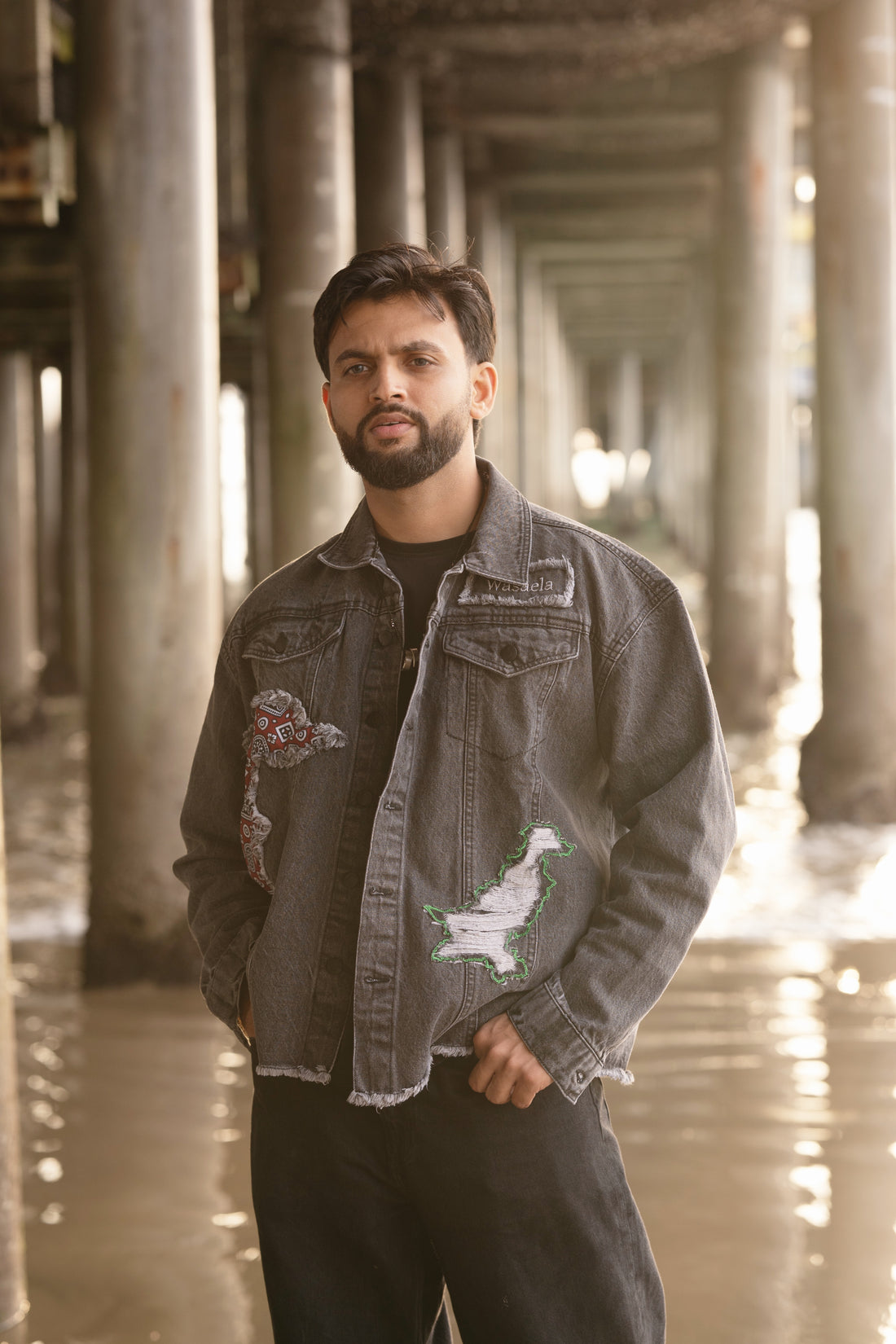 Man wearing a dark denim jacket with patches in an urban setting